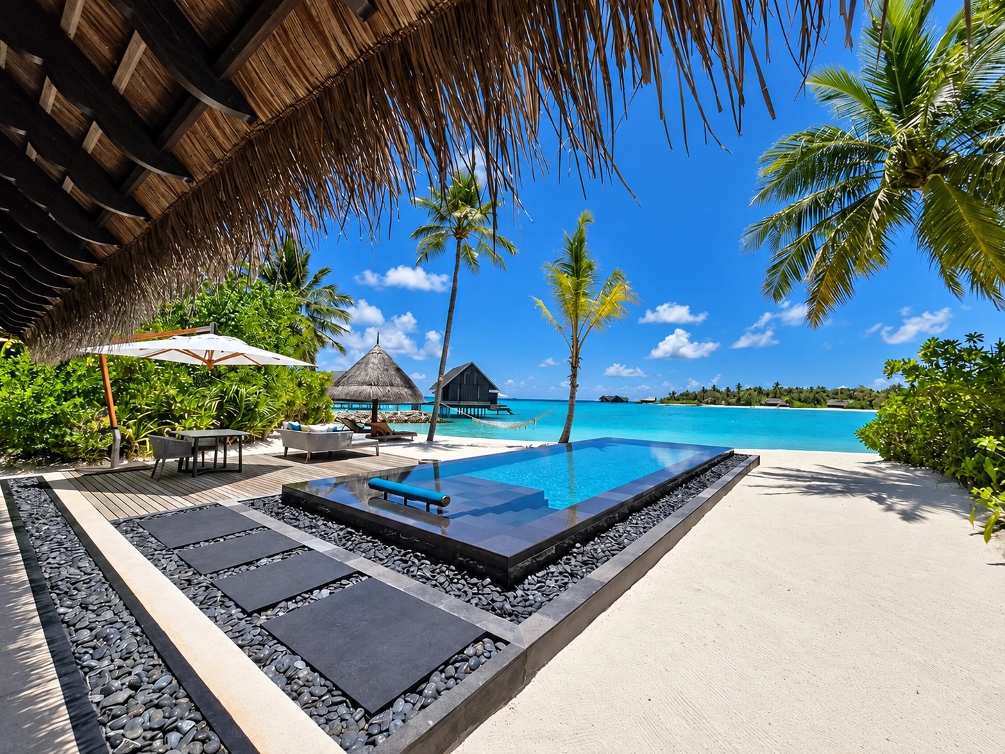 Piscina entre palmeras y playa en One&Only Reethi Rah