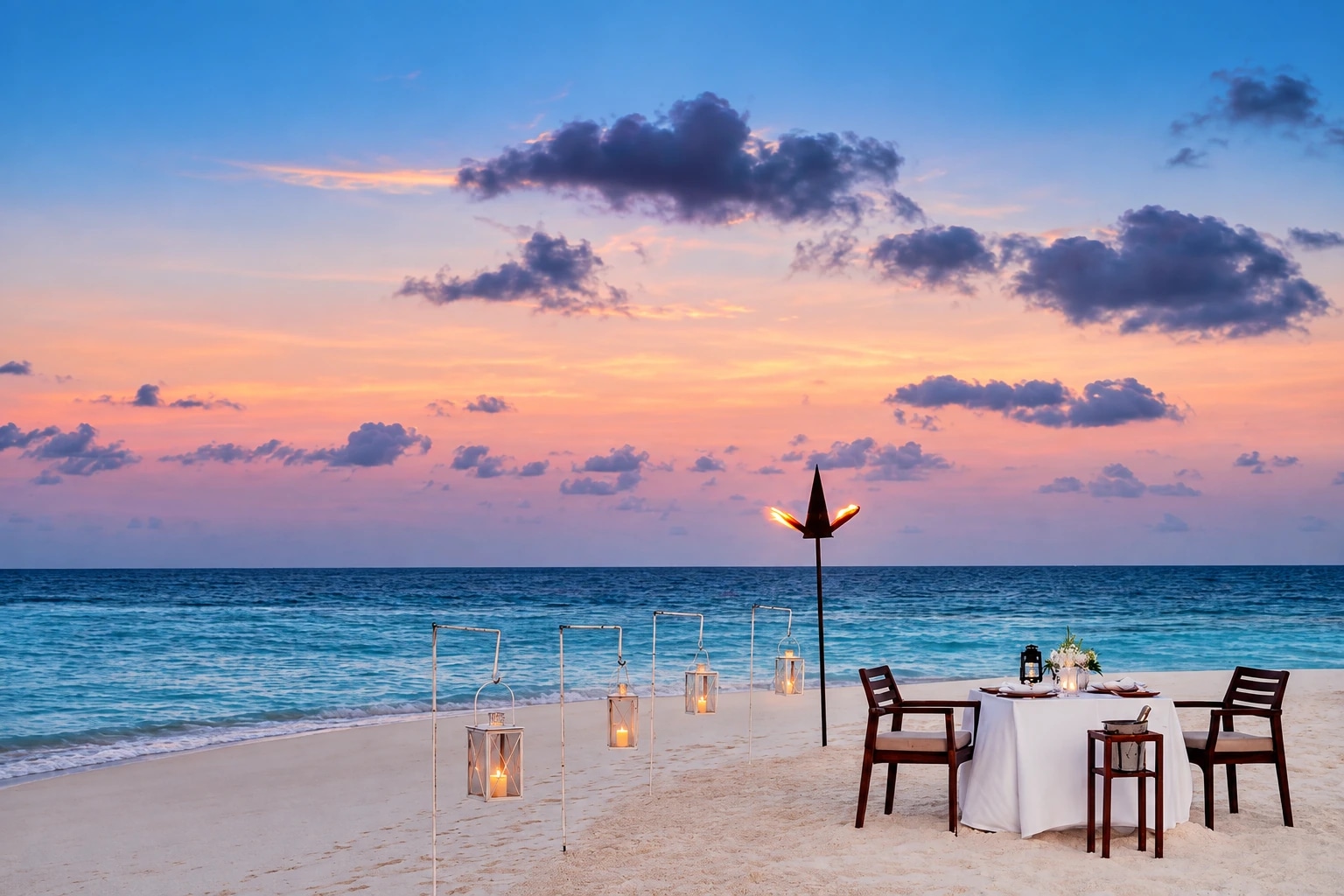 Mesa preparada en la playa al anochecer en One&Only Reethi Rah