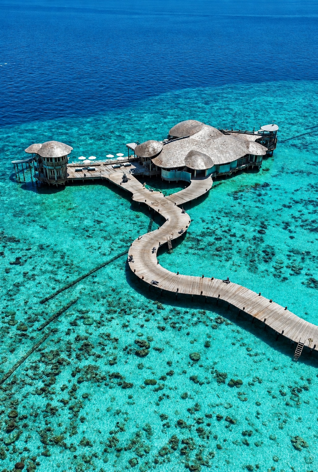 Vue aérienne de pavillons et d’une passerelle au-dessus du lagon de Soneva Fushi